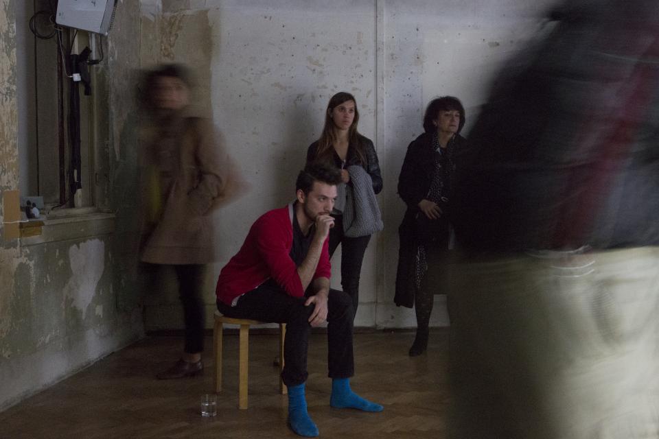 detail of performer seated surrounded by audience