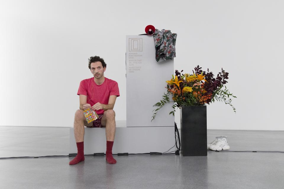 performer sitting next to podium, placing heart-shaped stickers on his face