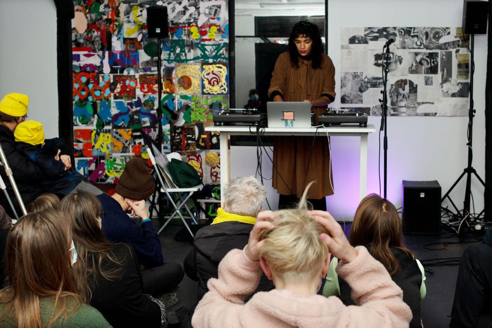 image of performer standing behind desk with turntables and computer