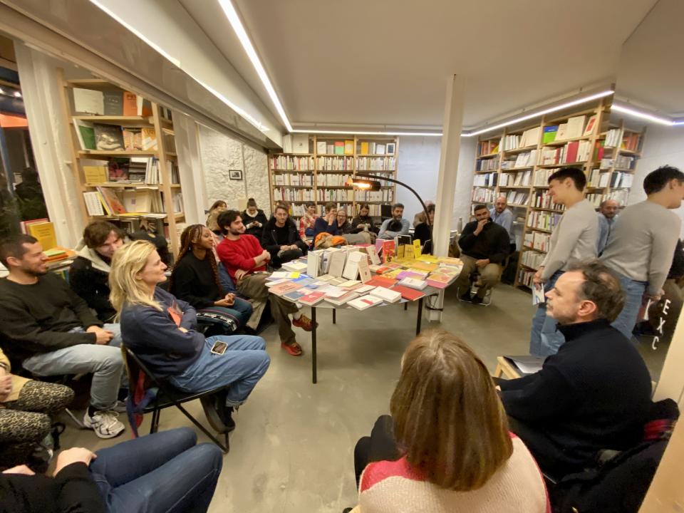 interior of a bookshop filled with seated audience and standing author
