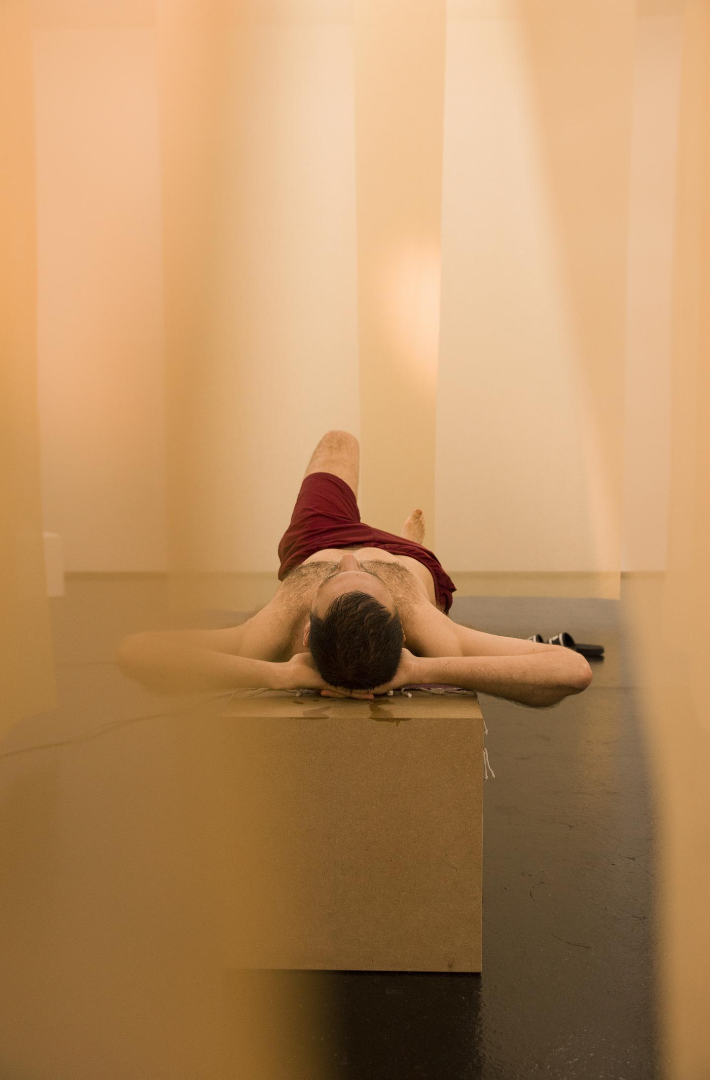 artist lying on wooden bench with hands behind his head